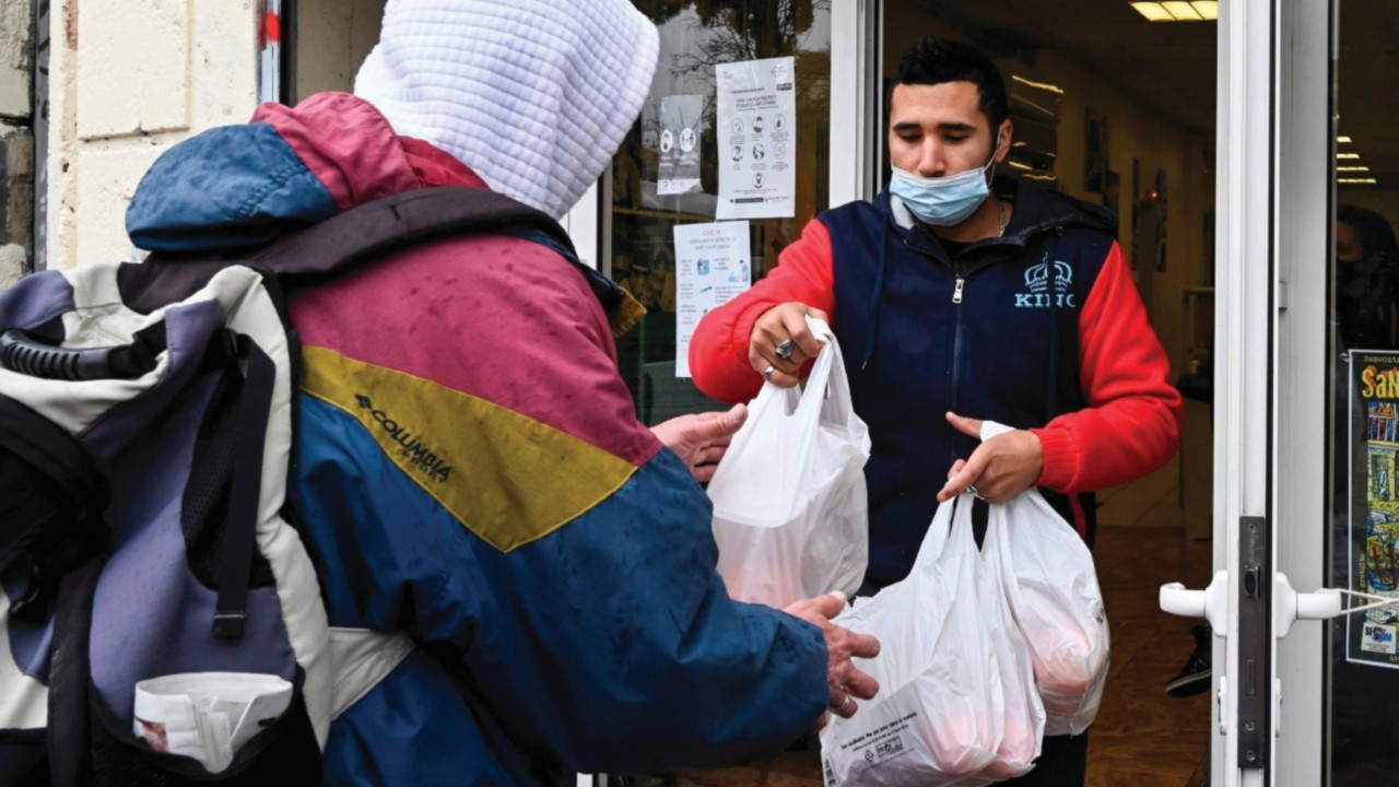 A volunteer gives packs of food to a man at the Noga, a social restaurant in Marseille, on December ...