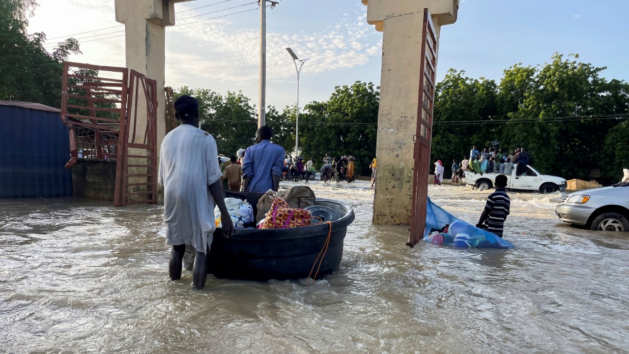 Flood victims push their belongings along a flooded road as they move to safety, in Maiduguri, ...